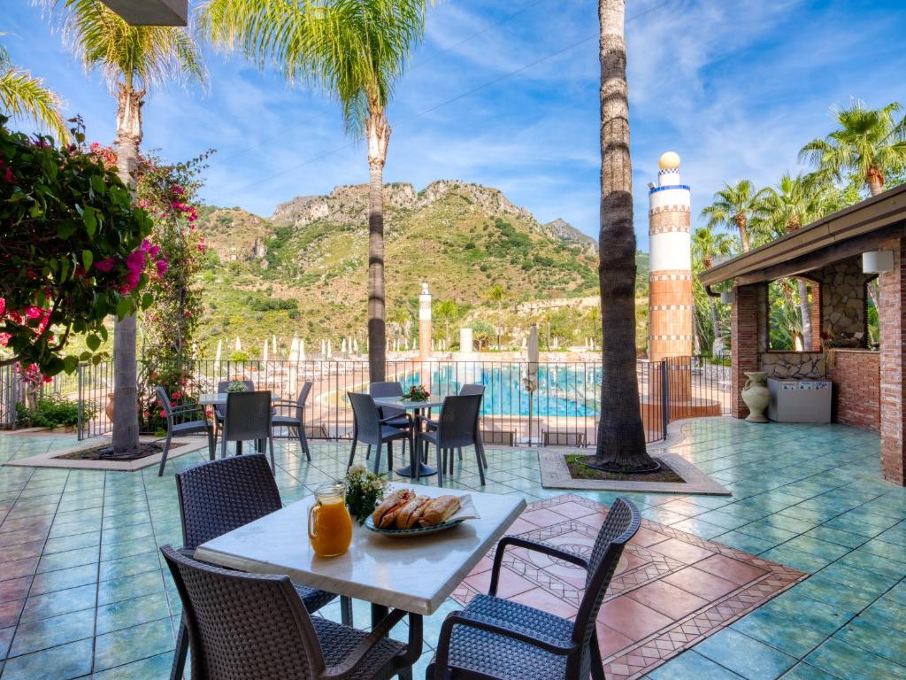 d'une terrasse avec une table, des chaises et un phare. dans l'établissement Hotel Olimpo le Terrazze, à Letojanni