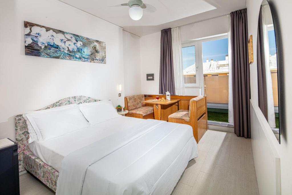 une chambre d'hôtel avec un lit, un bureau et une fenêtre dans l'établissement Hotel Alexander, à Bibione