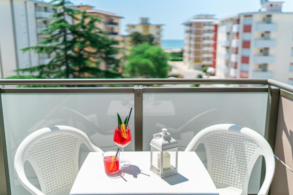 une table blanche avec deux verres sur un balcon dans l'établissement Hotel Alexander, à Bibione