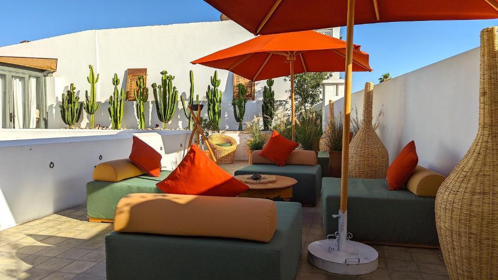 - une terrasse avec 2 canapés et un parasol dans l'établissement Riad Jardin Des Sens & Spa, à Marrakech