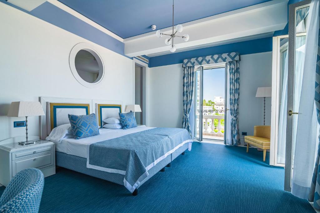 une chambre bleue avec un lit et une fenêtre dans l'établissement Casa Bianca Al Mare, à Lido di Jesolo