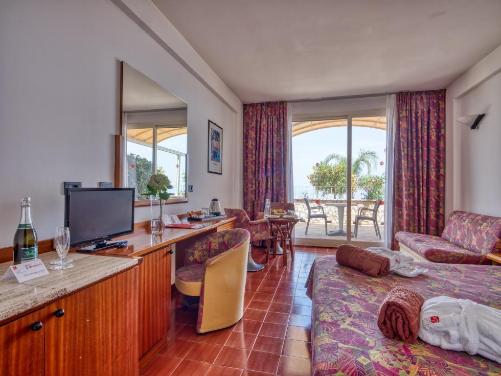 un salon avec une télévision et un canapé dans l'établissement Hotel Antares, à Letojanni