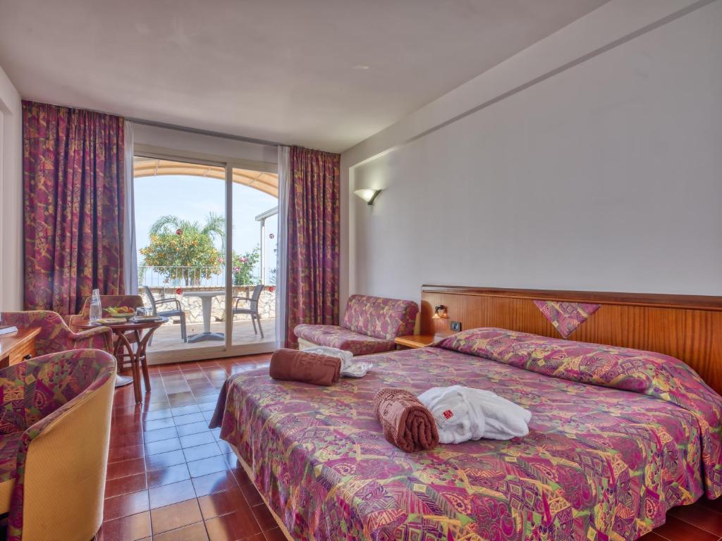 une chambre d'hôtel avec un lit sur lequel est allongée une personne dans l'établissement Hotel Antares, à Letojanni