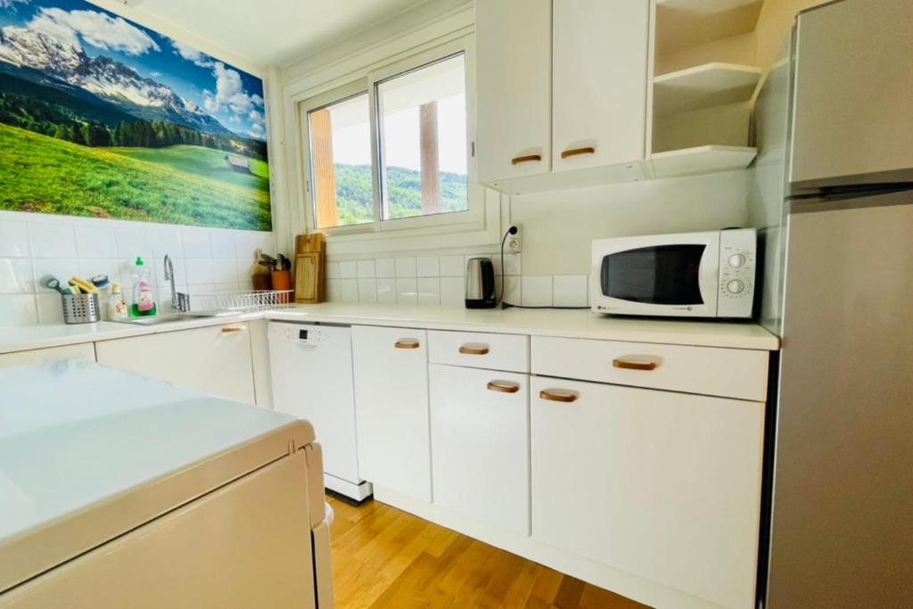 une cuisine avec des armoires blanches et un micro-ondes dans l'établissement 75m With Balcony Near The Slopes!, à La Salle Les Alpes