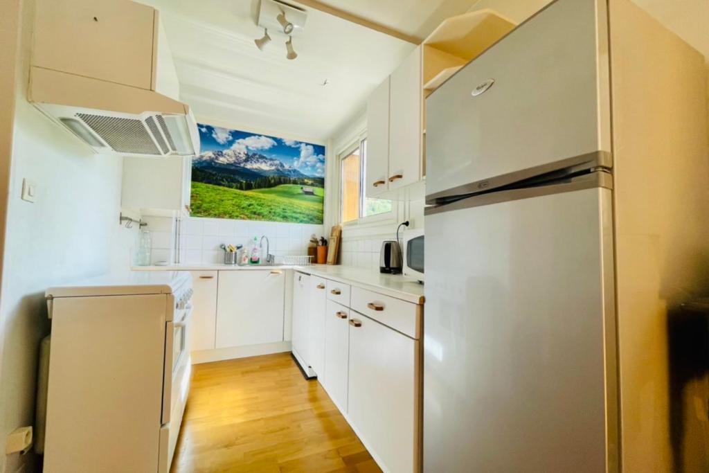 une cuisine avec des armoires blanches et un réfrigérateur en acier inoxydable dans l'établissement 75m With Balcony Near The Slopes!, à La Salle Les Alpes