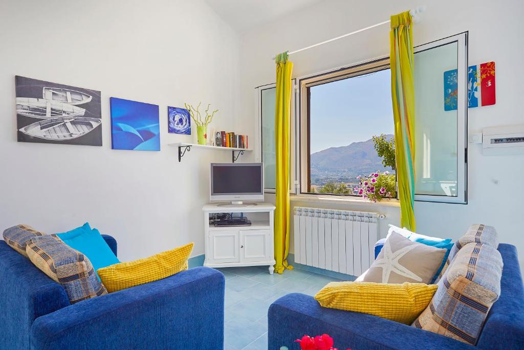 un salon avec deux chaises bleues et une télévision dans l'établissement Villa Del Sol - Scopello-Villas, à Scopello