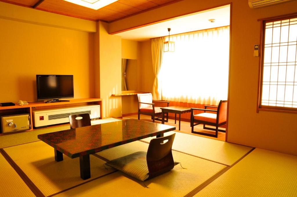 un salon avec une table et une télévision dans l'établissement Yumotoya, à Niigata 16 autres photos