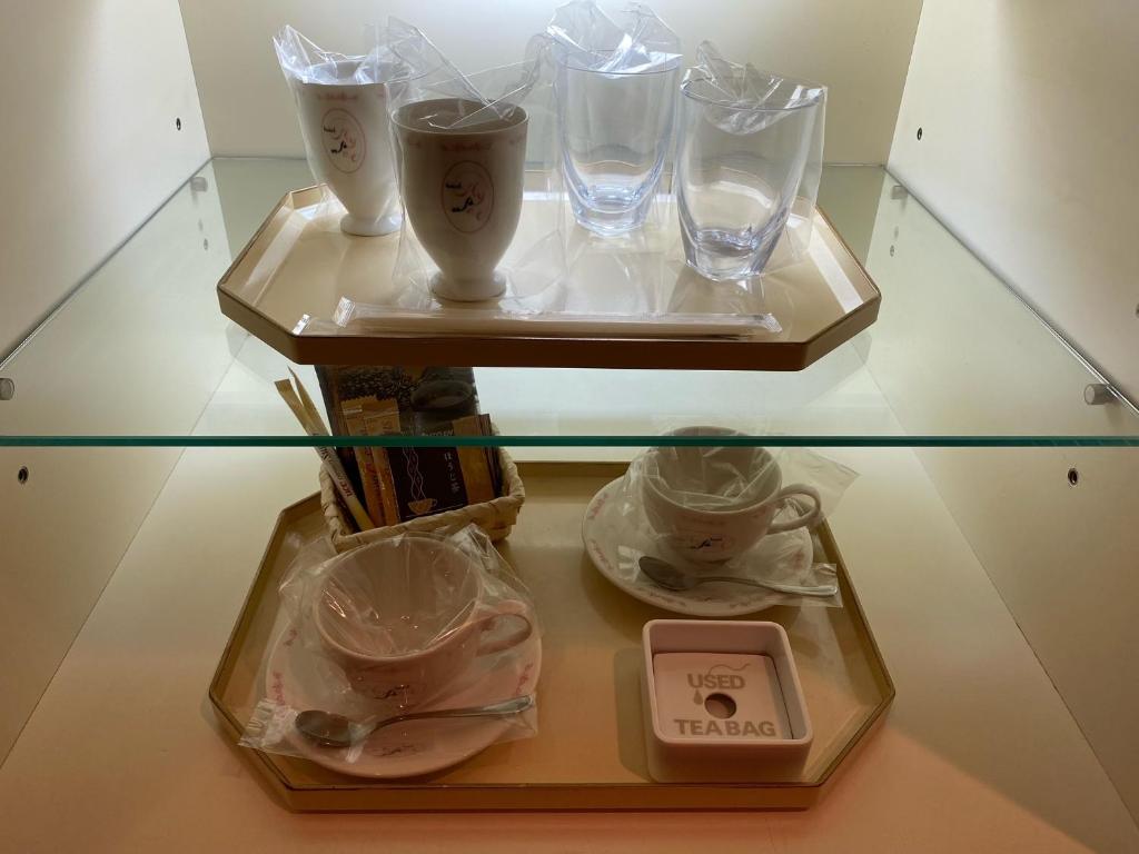 - une table en verre avec 2 plateaux avec des verres dans l'établissement Hotel Hyper (Adult Only), à Osaka