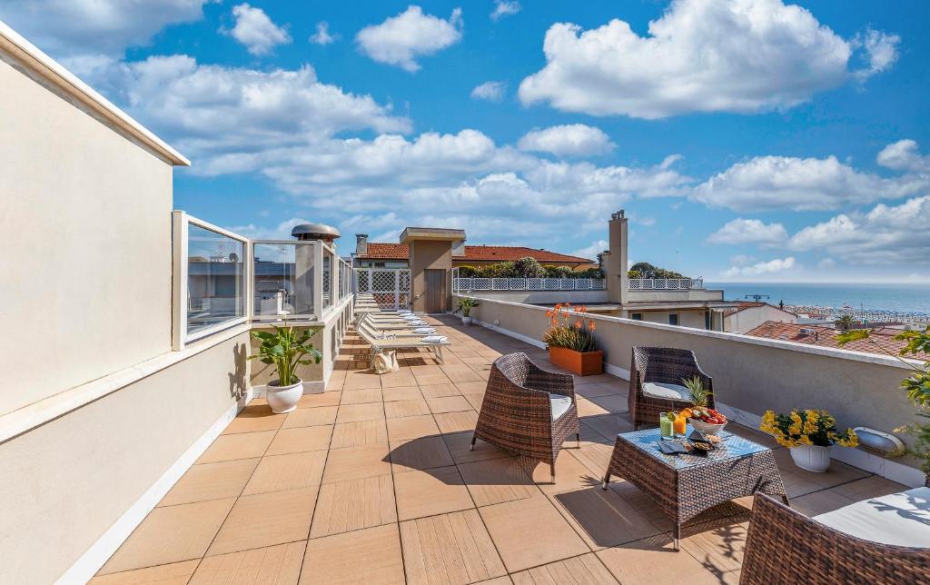 d'une terrasse avec des chaises et des tables sur un balcon. dans l'établissement Hotel Residence Esplanade, à Viareggio
