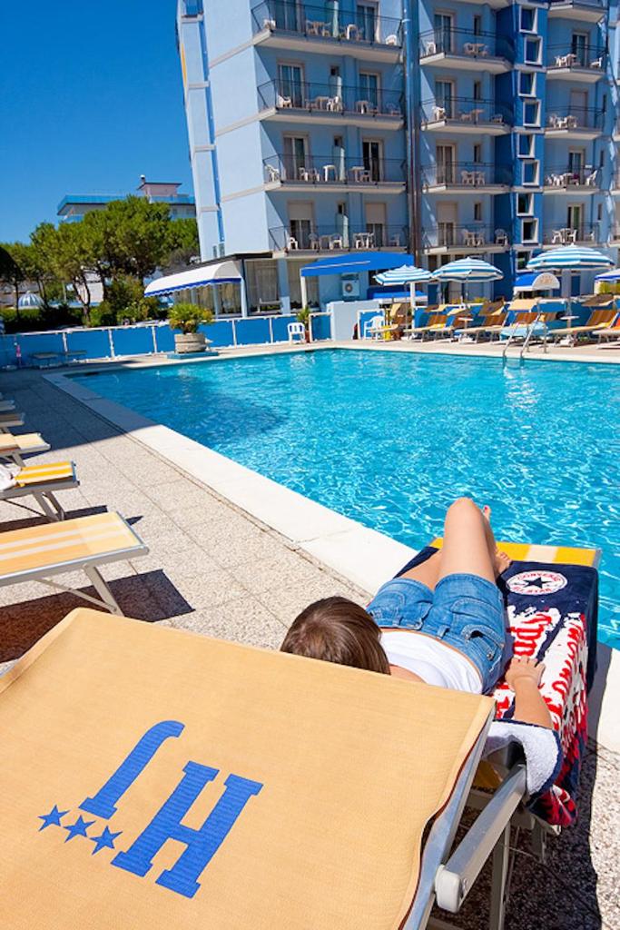 un enfant dormant sur une chaise longue à côté de la piscine dans l'établissement Hotel Jet, à Lido di Jesolo