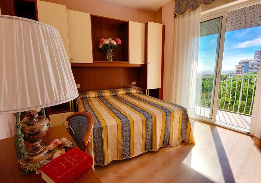 une chambre avec un lit, une lampe et une fenêtre dans l'établissement Hotel Jet, à Lido di Jesolo