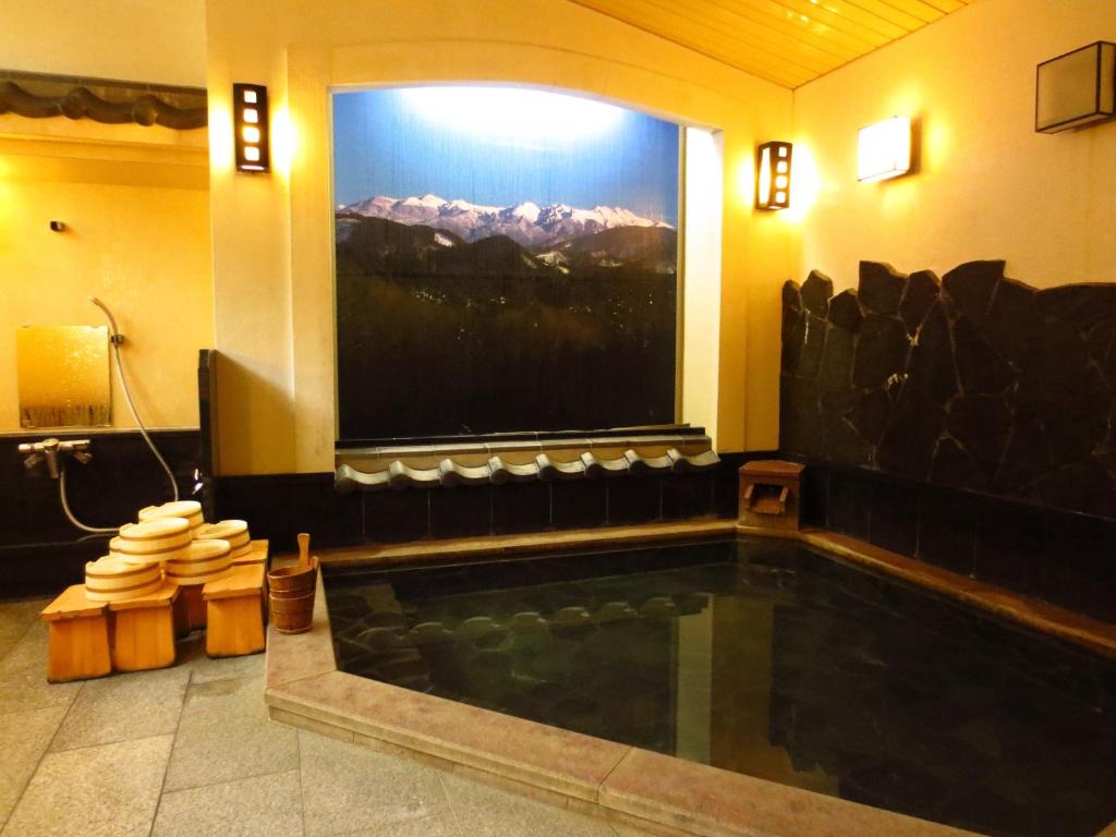La salle de bains est pourvue d'une piscine et d'une grande fenêtre. dans l'établissement Shitanda, à Takayama