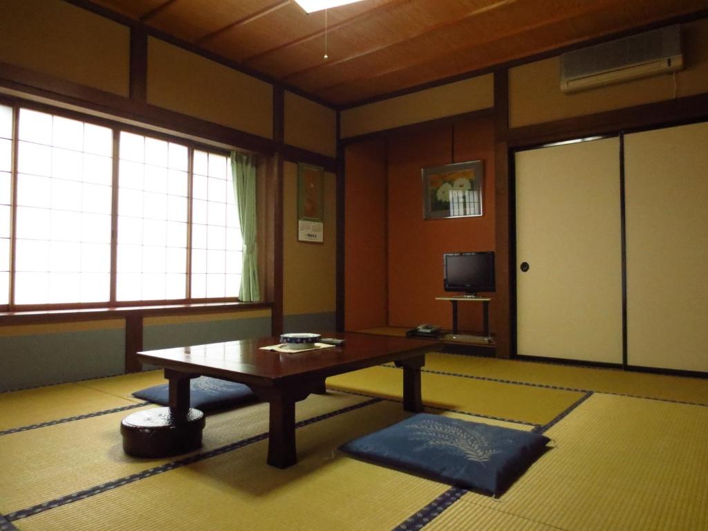 un salon avec une table et une télévision dans l'établissement Shitanda, à Takayama