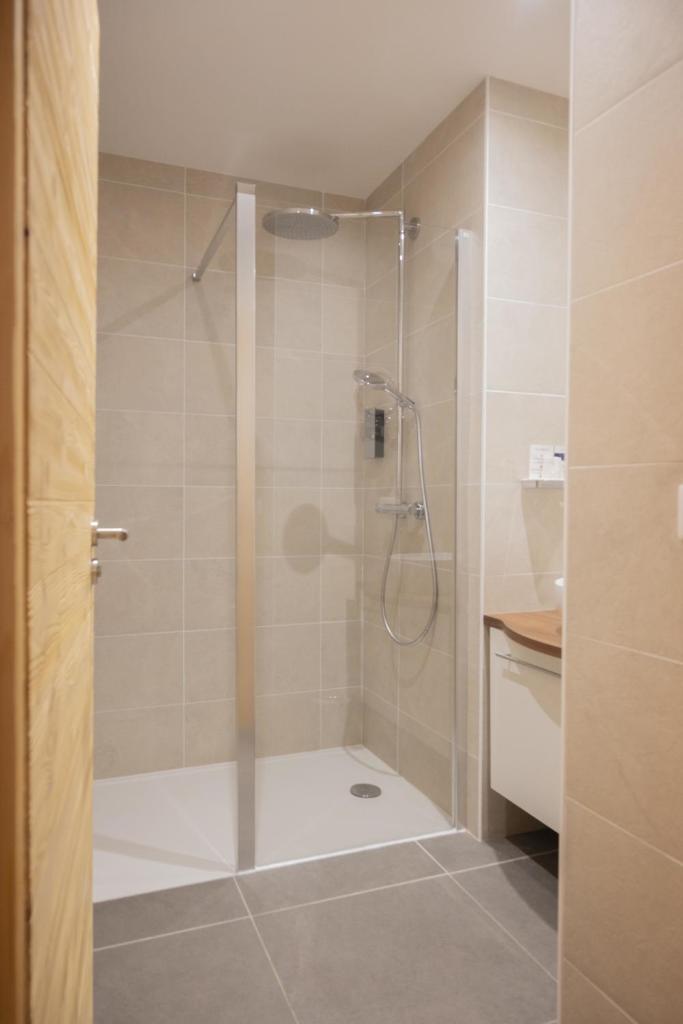 une douche avec une porte vitrée dans une salle de bain dans l'établissement Hotel Restaurant Mont Champ du Feu, à Belmont