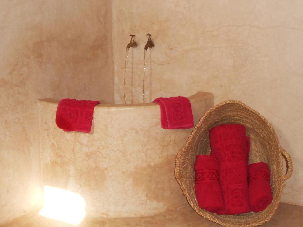 La salle de bains est pourvue d'une baignoire et de 2 serviettes rouges. dans l'établissement Riad Le Bel Oranger, à Marrakech