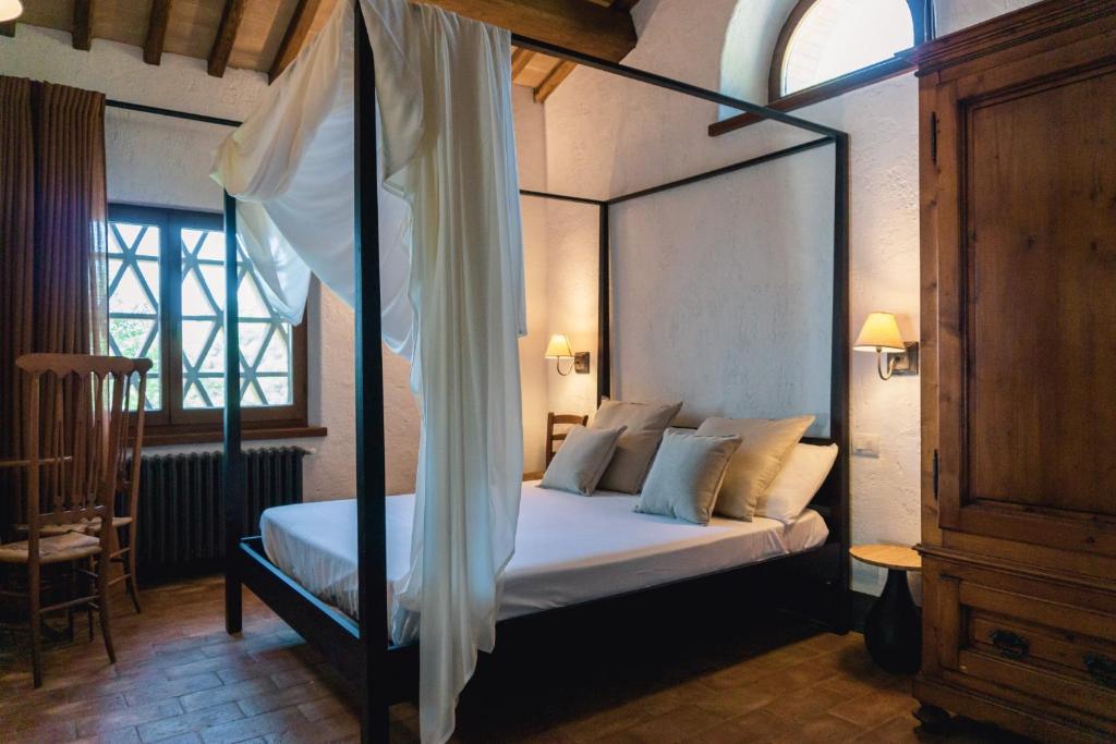 - une chambre avec un lit à baldaquin et des oreillers blancs dans l'établissement Villa Comunaglia - Privacy & Piscina Panoramica, à Niccone