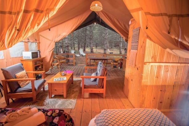 Cette chambre comprend une tente avec des chaises et une table. dans l'établissement Domaine de la Vitarelle Glamping, à Villanière