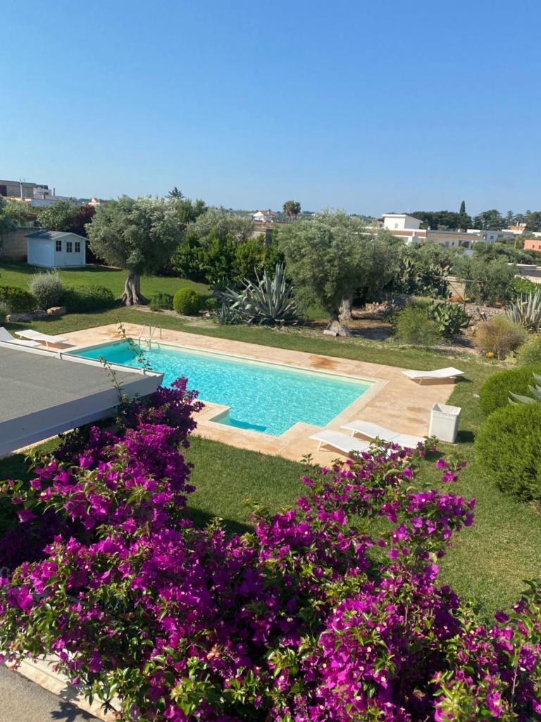 une vue d'une piscine avec des fleurs violettes dans l'établissement Luxury Villa Mariachiara, à Monopoli