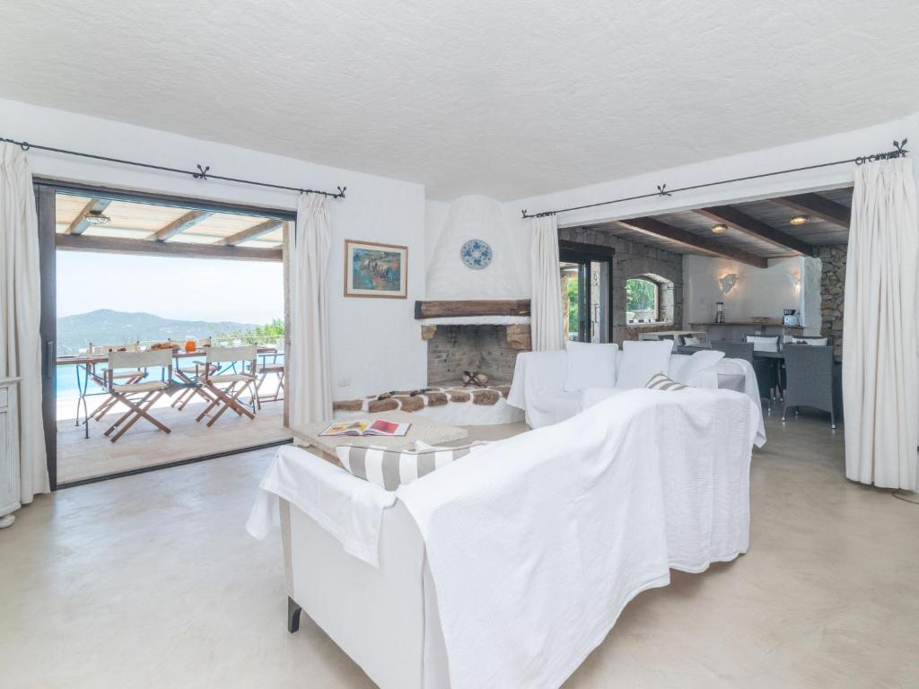 Elle comprend un salon doté d'un mobilier blanc et d'une cheminée. dans l'établissement Villa Paradiso by Interhome, à Porto Cervo
