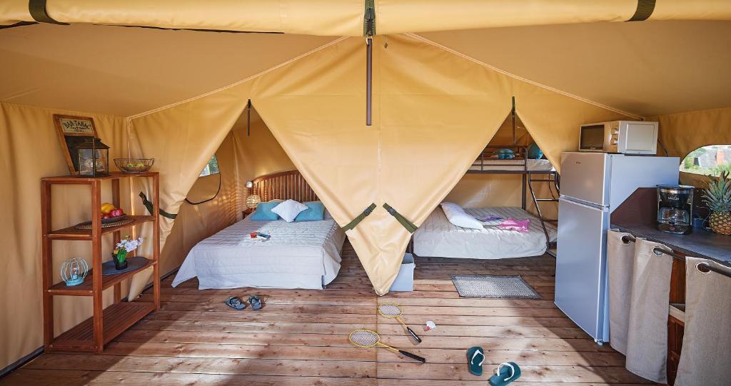 une chambre avec deux lits dans une tente dans l'établissement Camping des Papillons, à Lalizolle