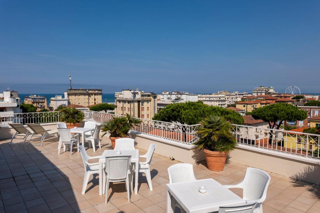 d'une terrasse avec des tables et des chaises blanches sur un balcon. dans l'établissement Hotel Sylvia, à Lido di Camaiore