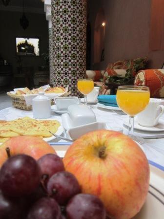 une table avec des pommes, des raisins et des verres de jus d'orange dans l'établissement Riad Dar Alia, à Rabat
