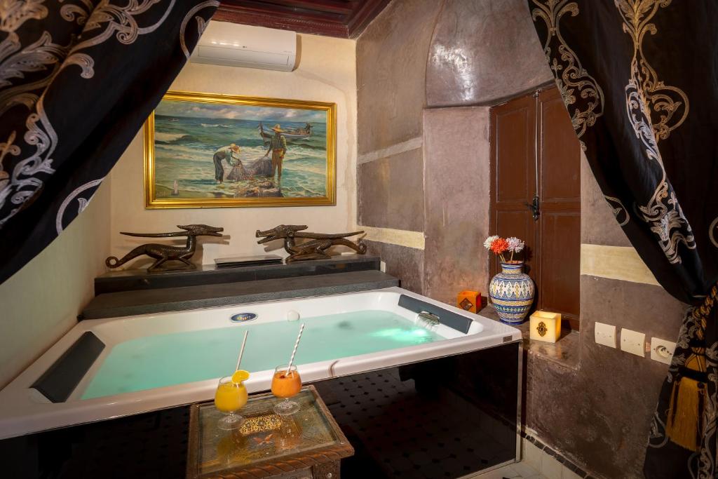 La salle de bains est pourvue d'une baignoire et d'une peinture murale. dans l'établissement Riad Ben Tachfine, à Marrakech