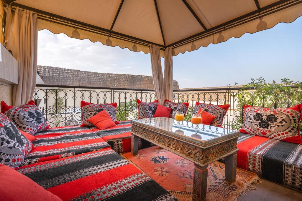 - une terrasse couverte avec des oreillers rouges et bleus et une table dans l'établissement Riad Ben Tachfine, à Marrakech