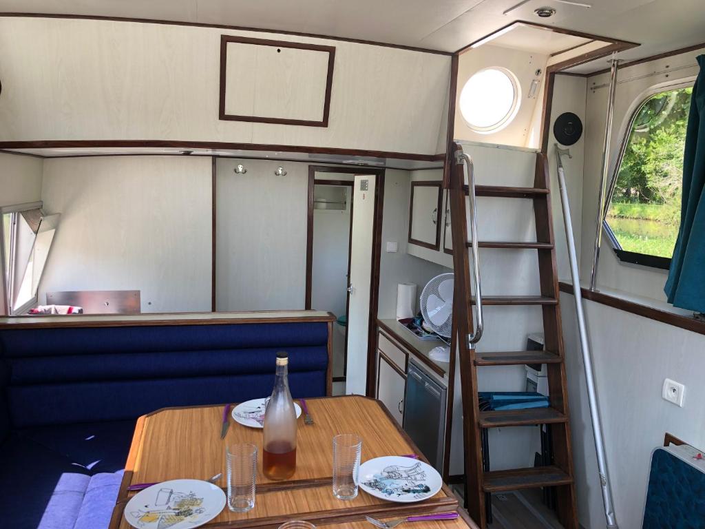 - une table à manger dans un coin salon avec une échelle dans l'établissement Le bateau du Foudre, à Châtillon-en-Bazois