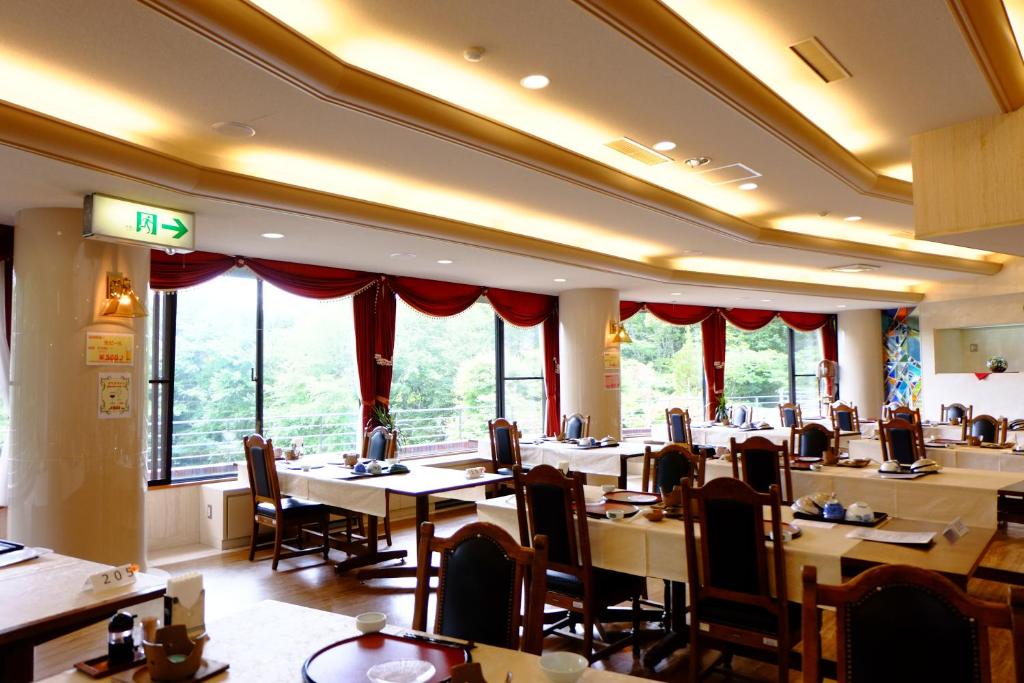 une salle à manger avec tables, chaises et fenêtres dans l'établissement Lake Yamanakako Shuzansou, à Yamanakako