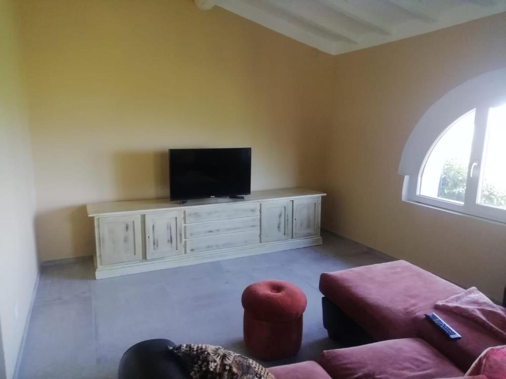 un salon avec une télévision à écran plat sur une armoire dans l'établissement Casa Quercioli, à Pulicciano