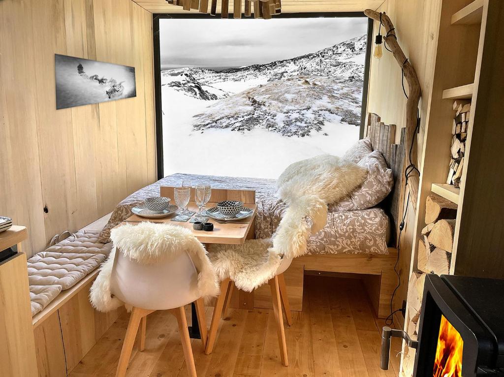 une petite chambre avec une table, des chaises et une fenêtre dans l'établissement atipic lodge, à Arette