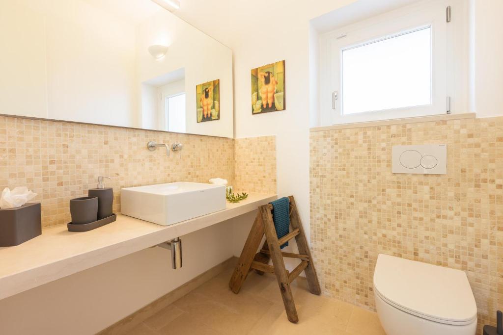 une salle de bain avec un lavabo, des toilettes et un miroir dans l'établissement Villa Panitria, à Ostuni