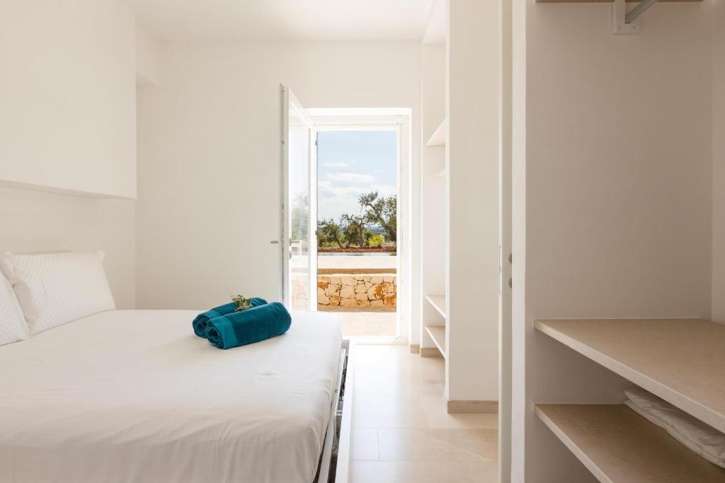 - une chambre blanche avec un sac bleu assis sur un lit dans l'établissement Villa Panitria, à Ostuni