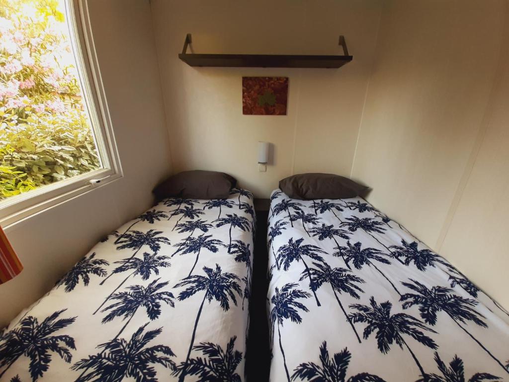 deux lits dans une petite pièce avec une fenêtre dans l'établissement mobile home entierement équipé, à La Roque-dʼAnthéron