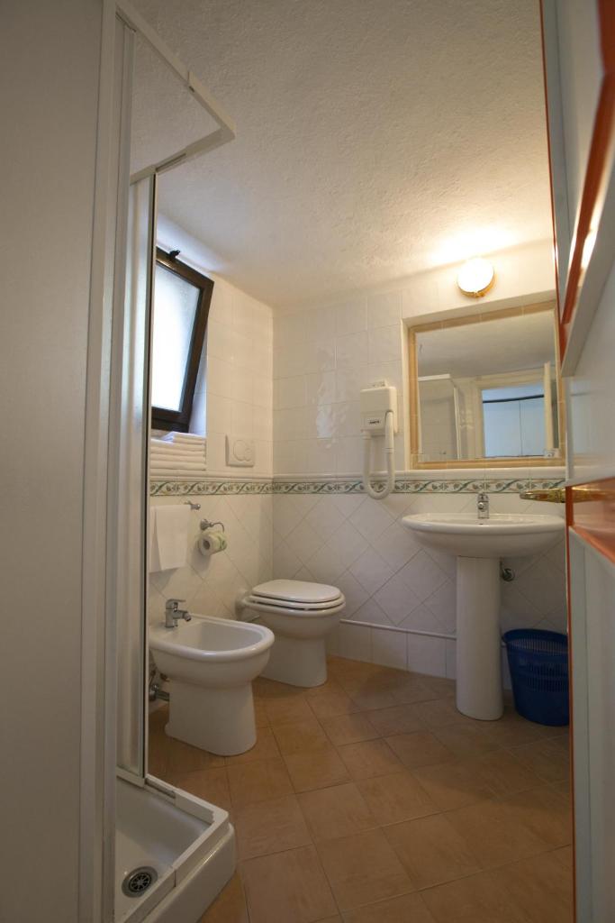 une salle de bain avec toilettes, lavabo et miroir dans l'établissement Hotel Cala di Mola, à Porto Azzurro