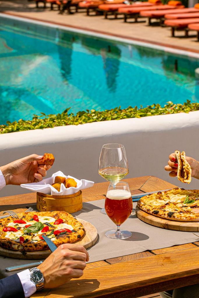 - une table avec trois pizzas et un verre de vin dans l'établissement Jumeirah Capri Palace, à Anacapri