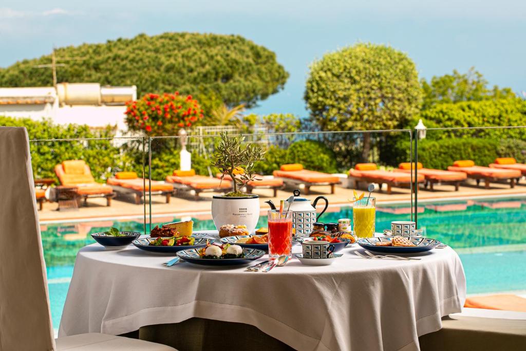 une table avec des assiettes de nourriture à côté d'une piscine dans l'établissement Jumeirah Capri Palace, à Anacapri 160 autres photos