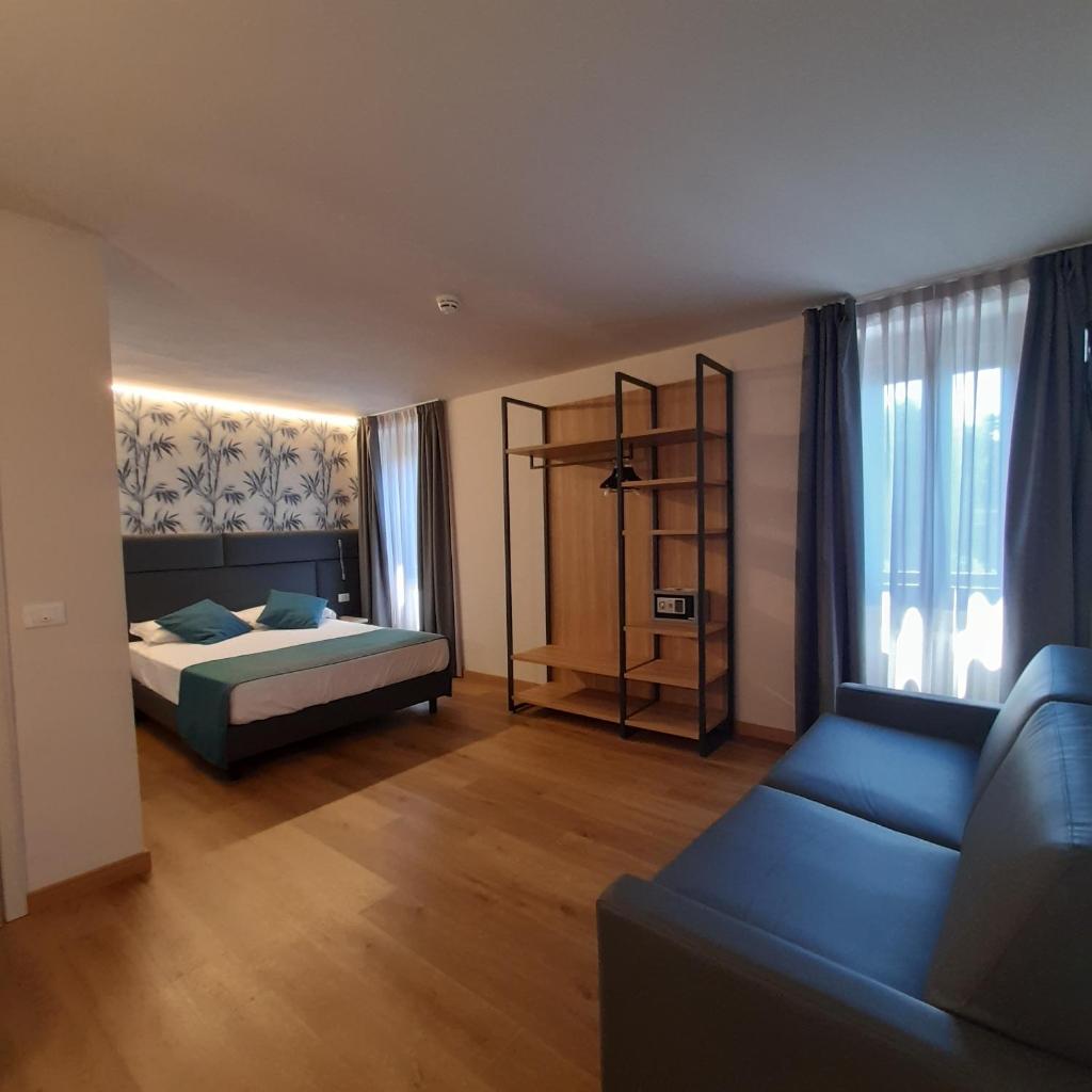 une chambre avec un lit et un canapé dans une pièce dans l'établissement Bike Hotel Touring Gardone Riviera & Wellness, à Gardone Riviera