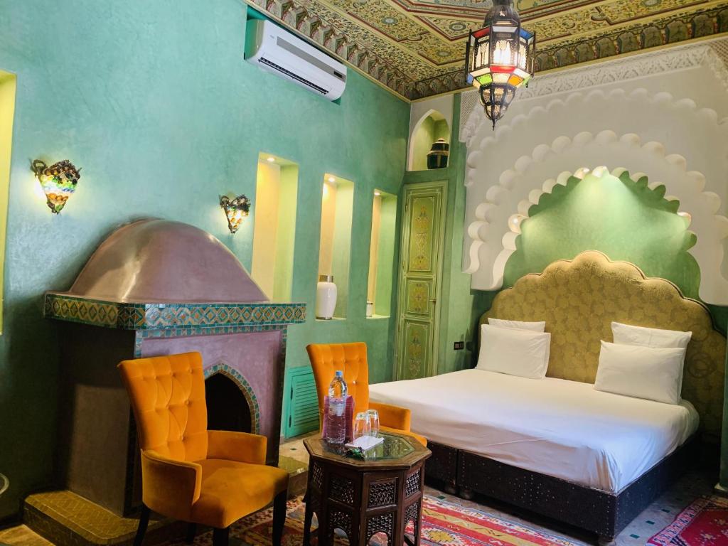 - une chambre avec un lit, une chaise et une cheminée dans l'établissement Riad Moullaoud, à Marrakech