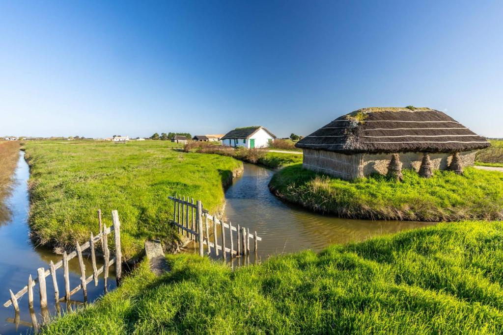 un ancien bâtiment avec un toit de chaume à côté d'une rivière dans l'établissement MH 150 camping 4 etoiles Bois Dormant 4 personnes, à Saint-Jean-de-Monts