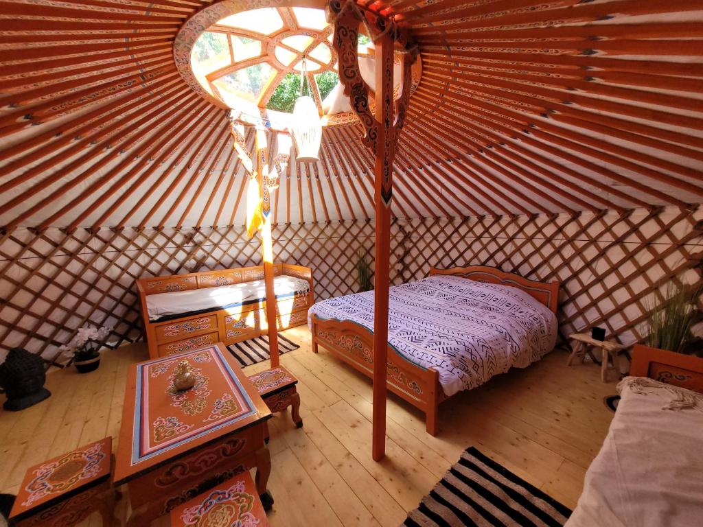- une chambre avec un lit et une table dans une yourte dans l'établissement Clos Des Monts, à Saint-Martin-des-Besaces