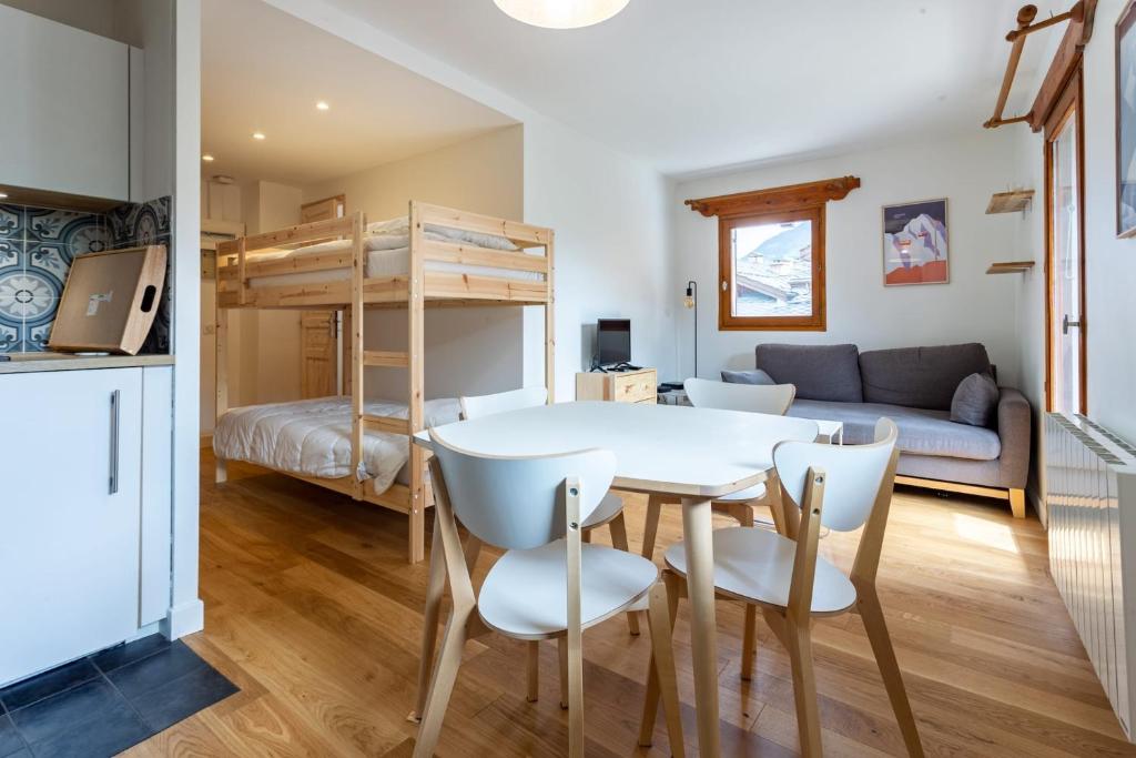 une chambre avec une table, des chaises et un lit superposé dans l'établissement TRÈS LUMINEUX Cocon avec BALCON près des pistes, à Courchevel