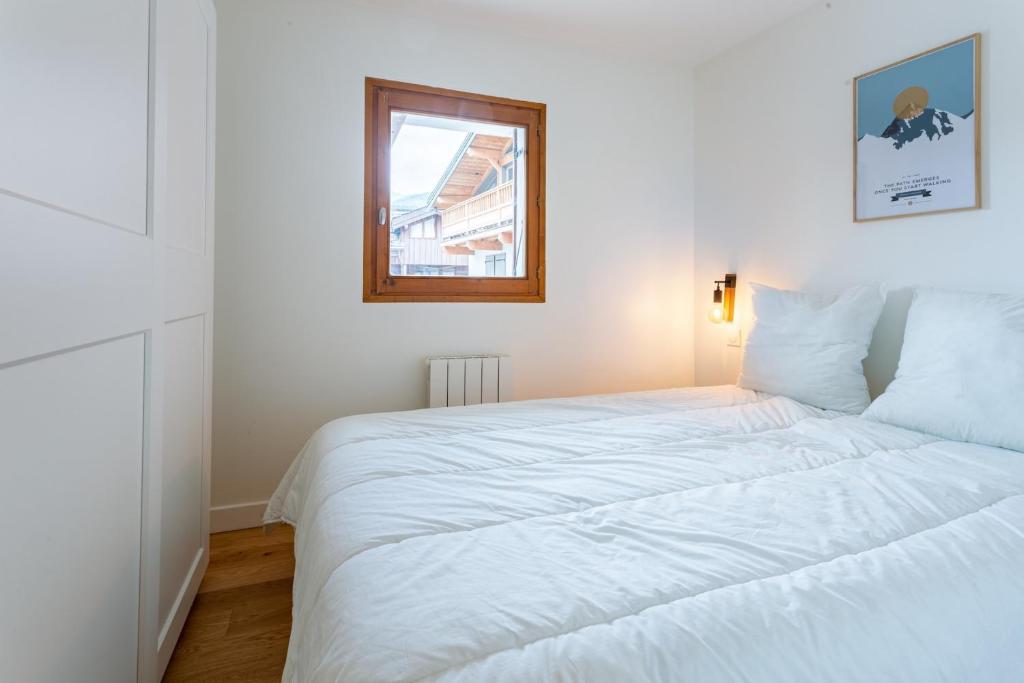 un lit blanc dans une chambre avec une fenêtre dans l'établissement TRÈS LUMINEUX Cocon avec BALCON près des pistes, à Courchevel