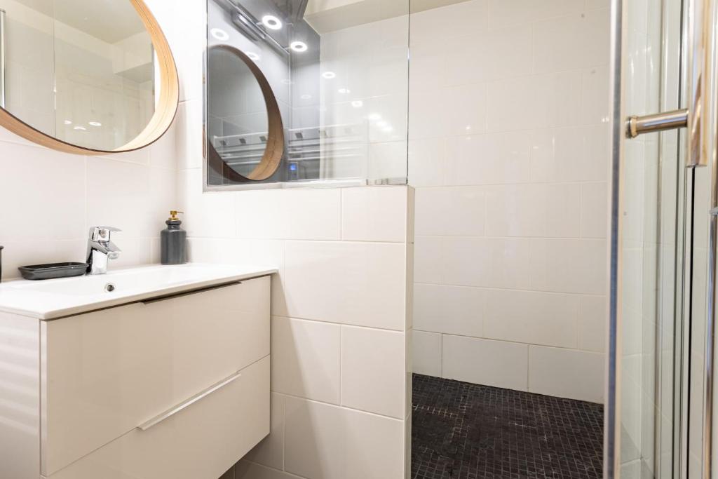 une salle de bain blanche avec un lavabo et un miroir dans l'établissement TRÈS LUMINEUX Cocon avec BALCON près des pistes, à Courchevel 2 autres photos