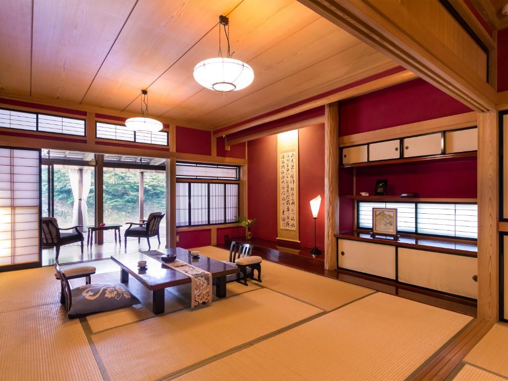un salon avec des murs rouges et une table et des chaises dans l'établissement Takanosukan, à Sekikawa