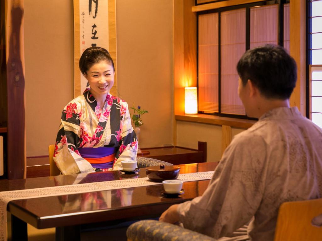 une femme assise à une table et parlant à un homme dans l'établissement Takanosukan, à Sekikawa