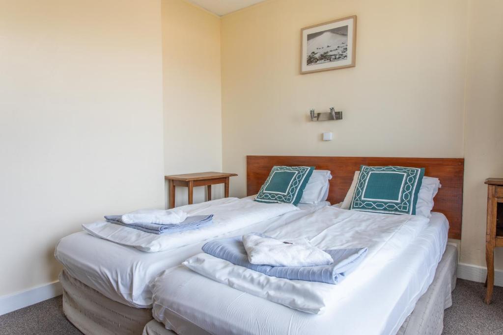 - une chambre avec 2 lits dotés de draps blancs et d'oreillers bleus dans l'établissement Hotel le Chamois, à L'Alpe-d'Huez