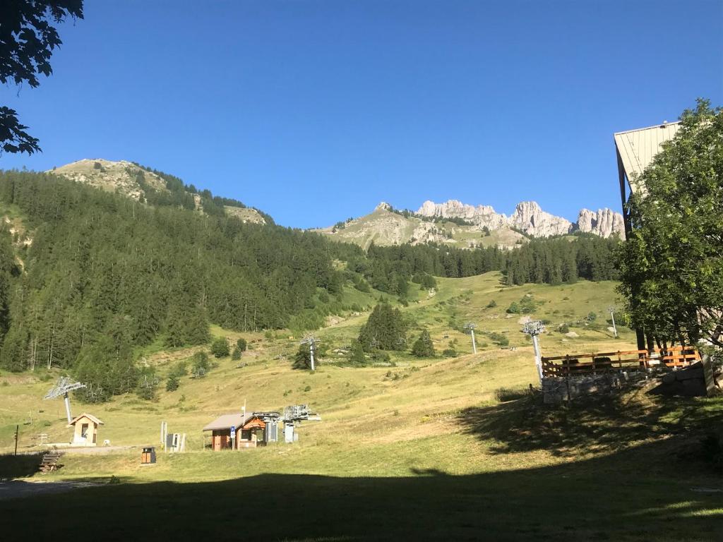 une vue sur une colline herbeuse avec des montagnes en arrière-plan dans l'établissement APPARTEMENT MONTAGNE, à Réallon