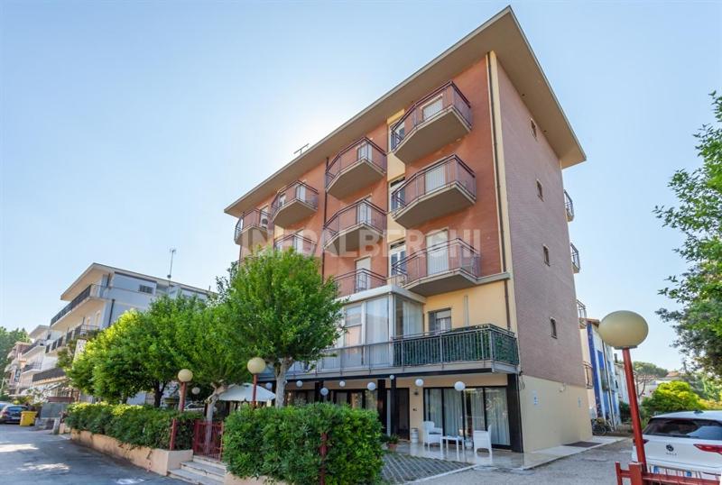 - un grand immeuble avec des voitures garées devant dans l'établissement Hotel Paradiso, à Rimini